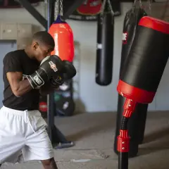 A boxer practices boxing drills in a gym, surrounded by various punching bags.