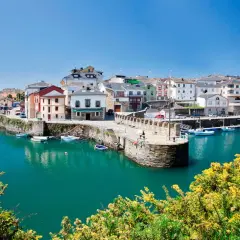 El pintoresco puerto vega, con sus casas coloridas y barcos meciéndose en aguas turquesas, bajo un cielo azul.