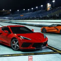 Dwa Chevrolet Corvette C8, czerwony i pomarańczowy, na nocnym torze wyścigowym. Sprawdź aktualną corvette c8 cena!