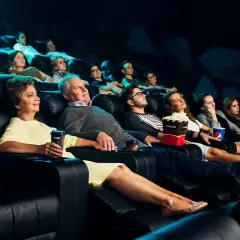 Ludzie w kinie Helios, zastanawiają się, ile kosztuje picie. Mają popcorn i napoje.