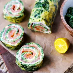 Spinat-Lachs-Röllchen, eine köstliche low carb Mahlzeit. Serviert mit frischem Spinat und Zitrone.