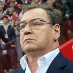 Trener w okularach z uwagą obserwuje trybuny, być może analizując potencjalnych kandydatów do reprezentacji.