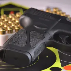 Pistolet i amunicja na tarczach strzeleckich, symbolizujące pozwolenie na broń do ochrony osobistej.