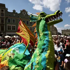 Kolorowy smok na krakowskim Rynku Głównym podczas Parady Smoków. Tłumy widzów podziwiają widowiskową postać.