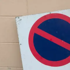 Znak b35 zakazu zatrzymywania się. Czerwone koło z czerwoną przekątną na niebieskim tle.