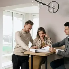 Para omówia plany z agentem nieruchomości, który pokazuje im dokumenty. Zastanawiają się, ile zarabia agent nieruchomości.