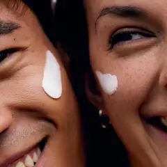 Coppia sorridente con crema sul viso, godendo dei benefici del vapore viso per una pelle radiosa.