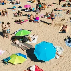 Wakacje pod gruszą na plaży. Ludzie opalają się, odpoczywają pod parasolami, ciesząc się słońcem i piaskiem.