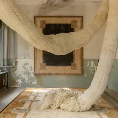 Installation artistique avec des cordes monumentales rappelant le passementier métier, drapant une pièce aux murs décrépis et sur des tapis graphiques.