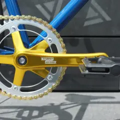 Złota korba Sturmey Archer i srebrna zębatka z nowym złotym łańcuchem, gotowe do wymiany w rowerze.