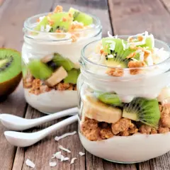 Två glas med yoghurt, granola, kiwi och banan. Perfekt mellanmål att ta med.
