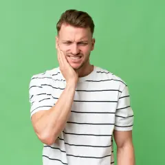 Mężczyzna z bólem zęba, zastanawia się, ile trzyma znieczulenie po wyrwaniu 8.