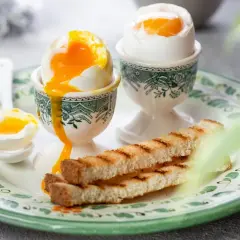 Idealne jajka na miękko, z płynnym żółtkiem, podane z grzankami. Dowiedz się, ile gotować jajka na miękko, by uzyskać taki efekt.