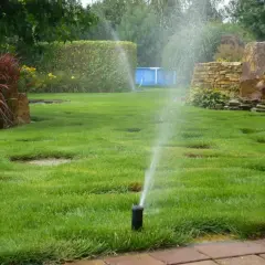 Zraszacz Rain Bird 3500 włączony, podlewający trawnik w ogrodzie.