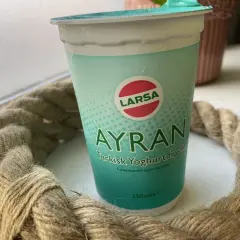 En kopp Larsa Ayran, turkisk yoghurt, står på ett bord. Perfekt för ett snabbt ayran recept.