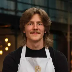 Jacob Jansson, en ung man med mustasch och långt hår, bär en vit kockförkläde.