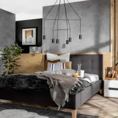 Nowoczesna, szara sypialnia inspiracje. Betonowa ściana, drewniane akcenty i minimalistyczne meble tworzą przytulną atmosferę.