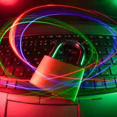 Kłódka na klawiaturze laptopa otoczona kolorowymi światłami, symbolizująca darmowy antywirus na laptopa i bezpieczeństwo danych.
