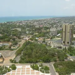 Widok na Lome, stolicę Togo, z dominującym złotym budynkiem i rozległym miastem w tle, nad którym rozciąga się ocean.