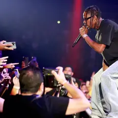 Travis Scott śpiewa na koncercie, a fani nagrywają go telefonami.