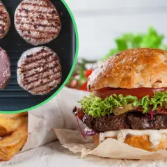 Gotowe burgery i surowe mięso na patelni grillowej, obok gotowy burger i frytki.