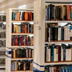 Rzędy regałów z książkami w bibliotece. Wśród nich można znaleźć pozycje dotyczące historii, w tym język chorwacki.