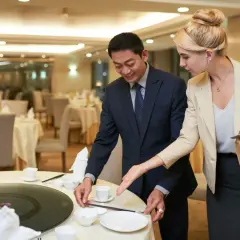 Ein Mann und eine Frau richten einen Tisch in einem Restaurant für ein Event her. Sie besprechen Details, die für das eventmanager gehalt wichtig sind.