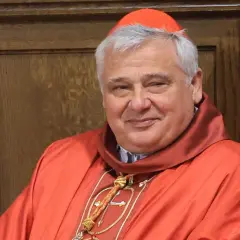 Uśmiechnięty kardynał w czerwonej sutannie i piusce. Kto jest nad biskupem? To on, w swojej uroczystej szacie.