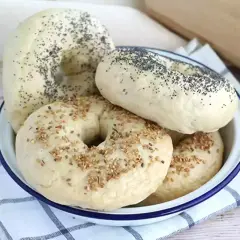 Färska bagels med vallmofrön och sesamfrön i en skål, redo för ett gott bagels recept.