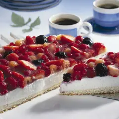 Eine einfache Torte mit frischen Beeren, bedeckt mit Tortenguss. Daneben zwei Tassen Kaffee.