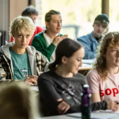 Młodzi ludzie na lekcji, zastanawiają się, fanfik co to. Jedna z dziewczyn ma blond włosy i patrzy wprost.