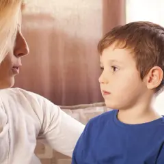 Kobieta rozmawia z chłopcem, który ma problemy z mową. Wsparcie w walce z afazją u dzieci.