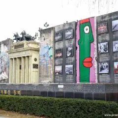 Fragment muru berlińskiego, gdzie jest, ozdobiony graffiti i zdjęciami z historii Niemiec.