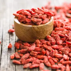 Suszone jagody goji rozsypane wokół drewnianej miseczki. Idealne do deserów, smoothie i jako zdrowa przekąska.
