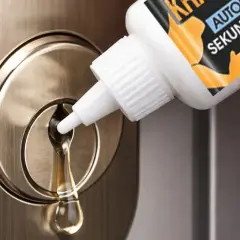 Une goutte de liquide s'écoule d'un flacon sur une serrure. Une astuce pour comment enlever de la colle dans une serrure.