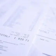 Stosy paragonów z widocznym napisem "TOTAL". Jeden z nich pokazuje kwotę 1 938,71, inny 716,49. Wsto oss.