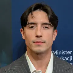 Dawid Kwiatkowski w szarym garniturze. Jego wzrost jest imponujący, a spojrzenie przyciąga uwagę.