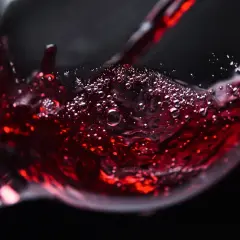 Czerwone wino bez cukru, z bąbelkami unoszącymi się na powierzchni, nalewane do kieliszka.
