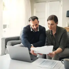 Para, analizując dokumenty i laptop, szuka odpowiedzi, gdzie najłatwiej dostać kredyt konsolidacyjny.
