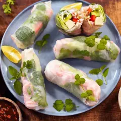 Färska sommarrullar med räkor och grönsaker, serverade med en smakrik vietnamesisk sås och limeklyftor.