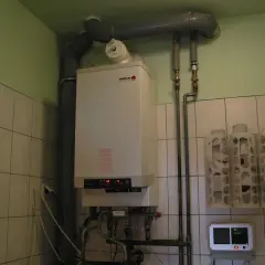 Kocioł gazowy Broetje, który pokazuje, jak ogrzewane są bloki. Obok wiszą uchwyty na papier toaletowy.