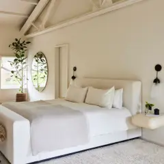 Serene bedroom with a large bed, fluffy stools, and a plant, creating positive energy placement feng shui bedroom vibes.