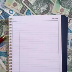 Notatnik i długopis na stosie polskich banknotów. Czy to miejsce na zapisanie, ile zarabia przewodniczący rady miasta?
