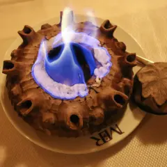 Caffè alla Valdostana in fiamme, servito in una coppa di terracotta con un coperchio intagliato.