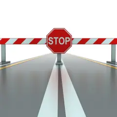 Bariera z napisem STOP na drodze, symbolizująca zakazy jazdy i utrudnienia.