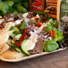 En läcker tallrik med iskender kebab, fylld med kött, grönsaker, bröd och såser. Perfekt för en smakrik måltid.