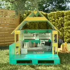 Ein farbenfrohes Spielhaus, das zum spielhaus selber bauen inspiriert. Mit Palettenboden, Kissen und Spielzeug im Garten.