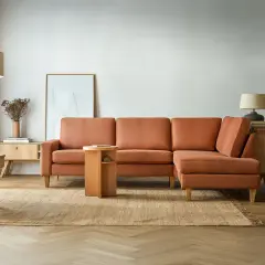 Ruda kanapa w salonie z dodatkami: lampa, stolik, dywan, obraz.