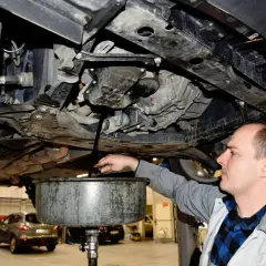 Mechanik spuszcza olej z samochodu. Zastanawiasz się, ile trwa wymiana oleju w samochodzie? Zwykle to szybka czynność.