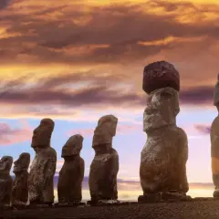 Kamienne posągi Moai na Wyspie Wielkanocnej o zachodzie słońca.